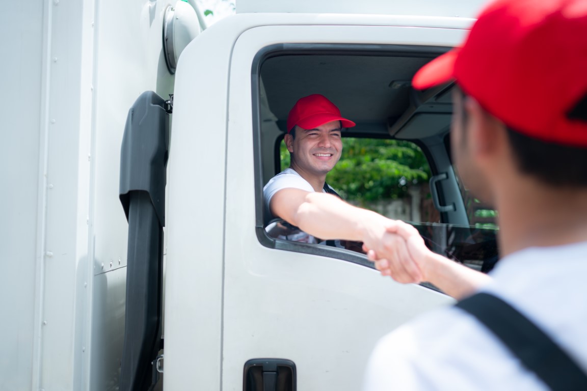 Delivery man in red cap and uniform handshaking each other after finishing deliveries.